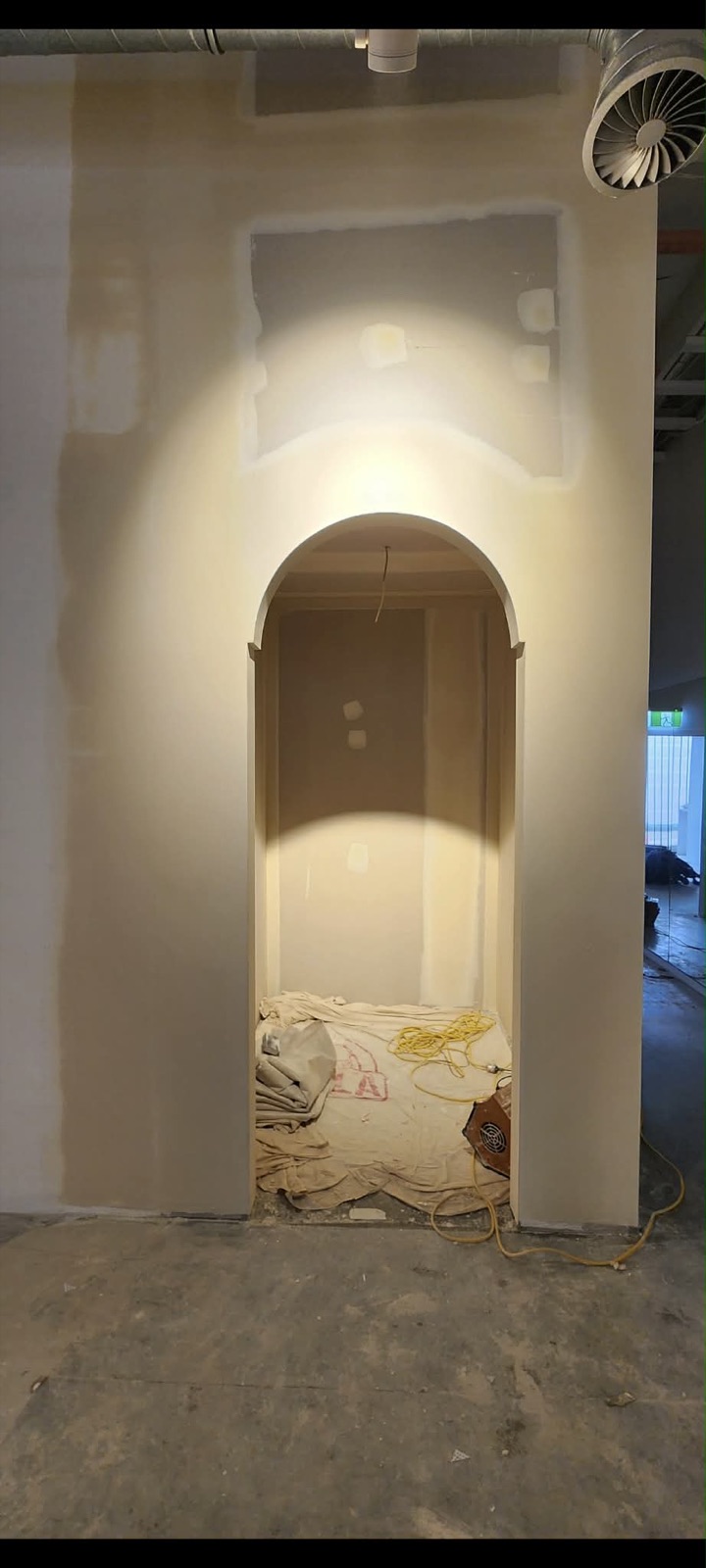 Tall arched plaster opening with clean curved returns in progress.