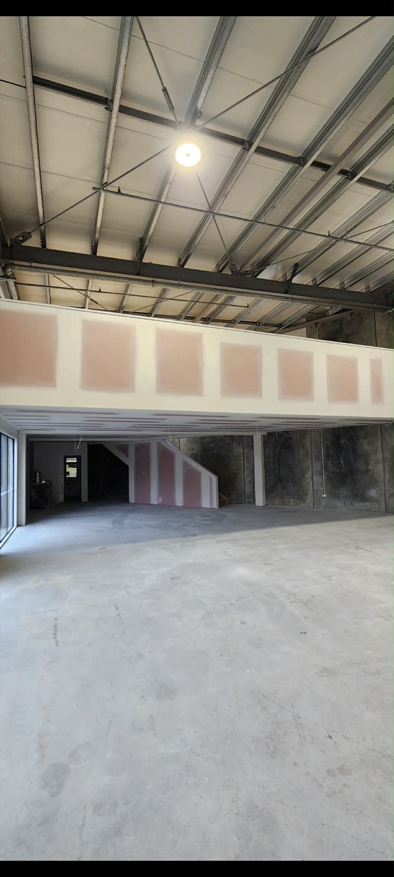 Commercial mezzanine fitout with large plasterboard wall sections and open industrial ceiling.