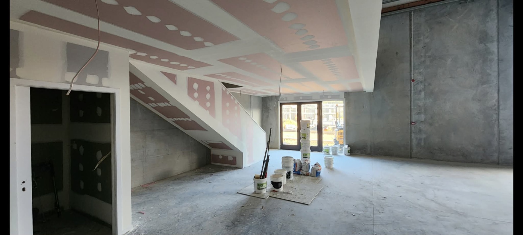 Commercial stair bulkhead with pink plasterboard sections and concrete walls.
