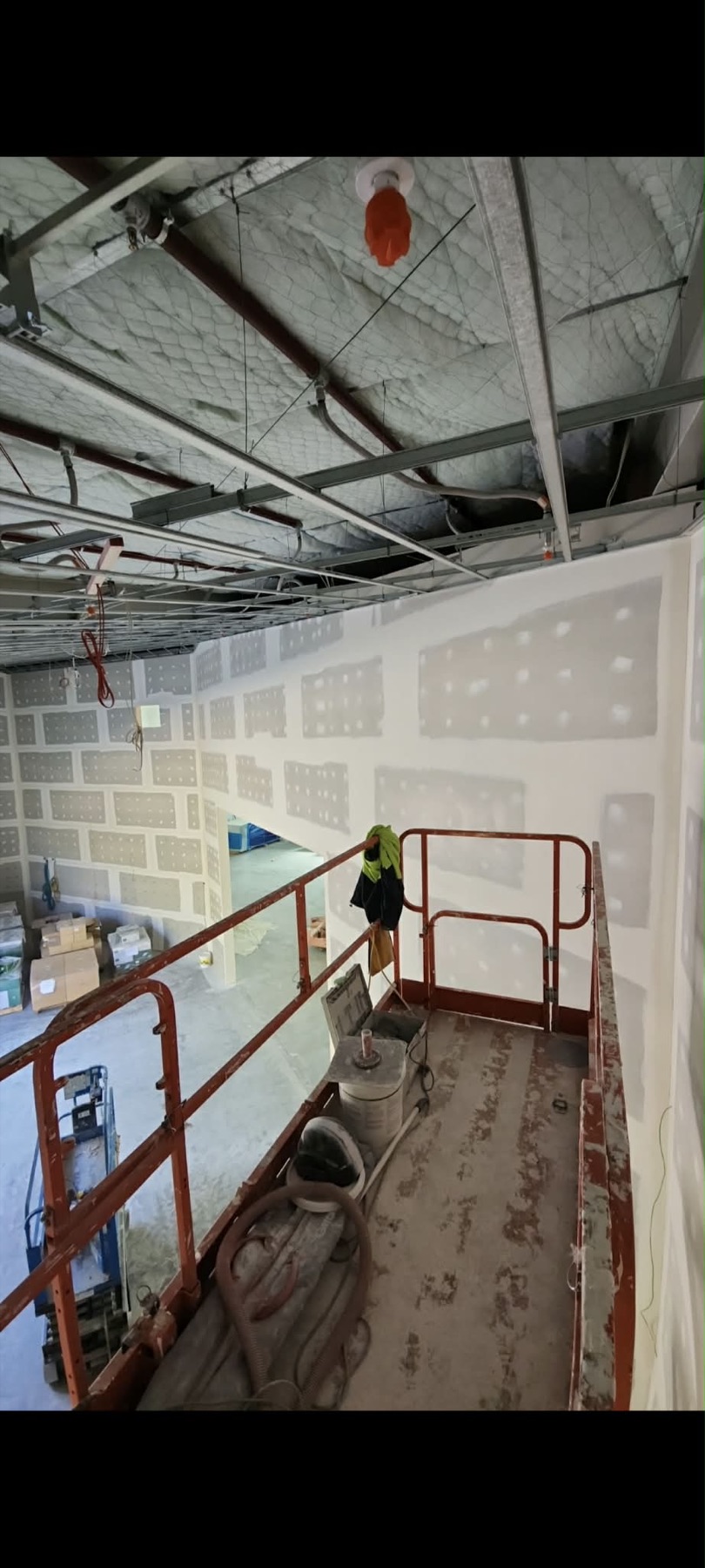Commercial interior with suspended ceiling grid, services, and stopped plasterboard walls.