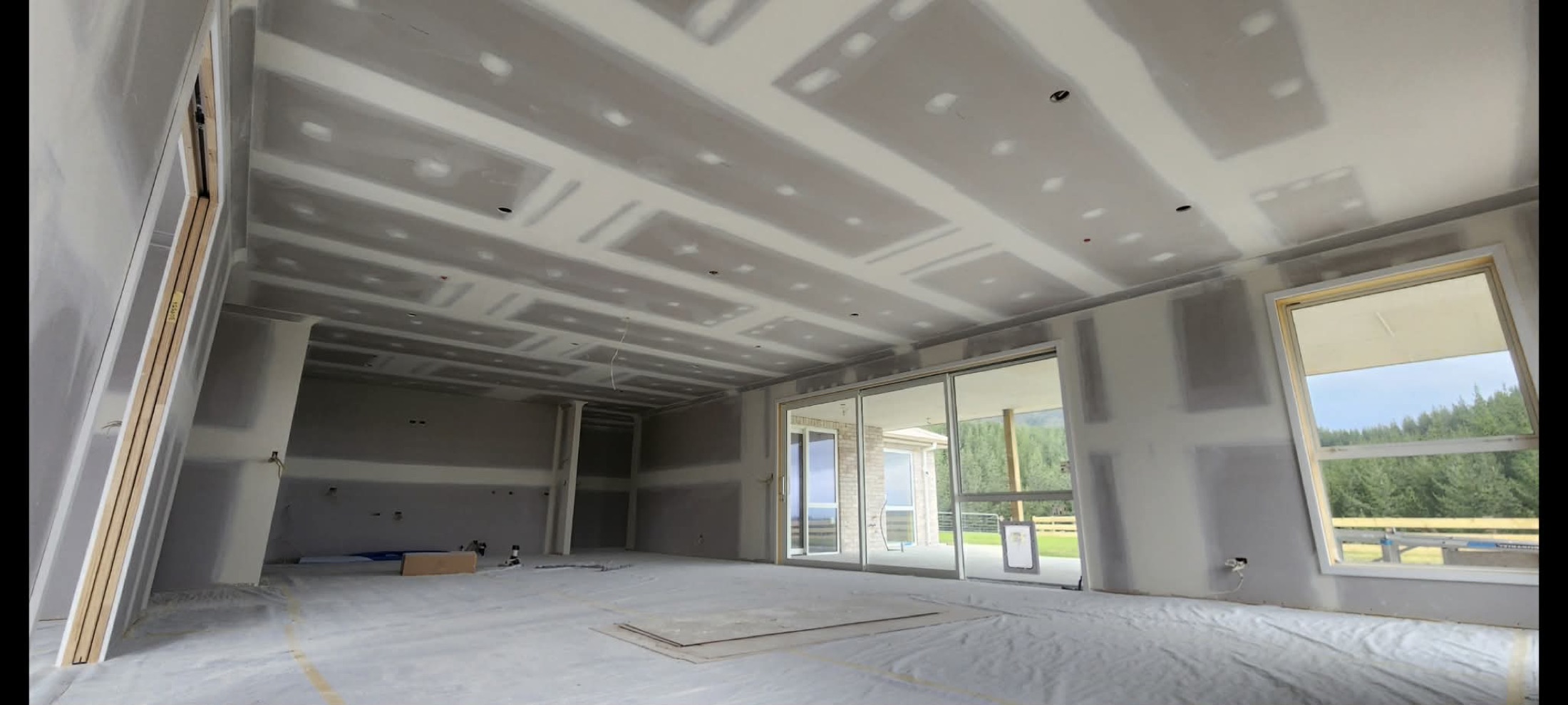 Large residential interior in progress with coffered plaster ceilings, clean wall stopping, and natural light.