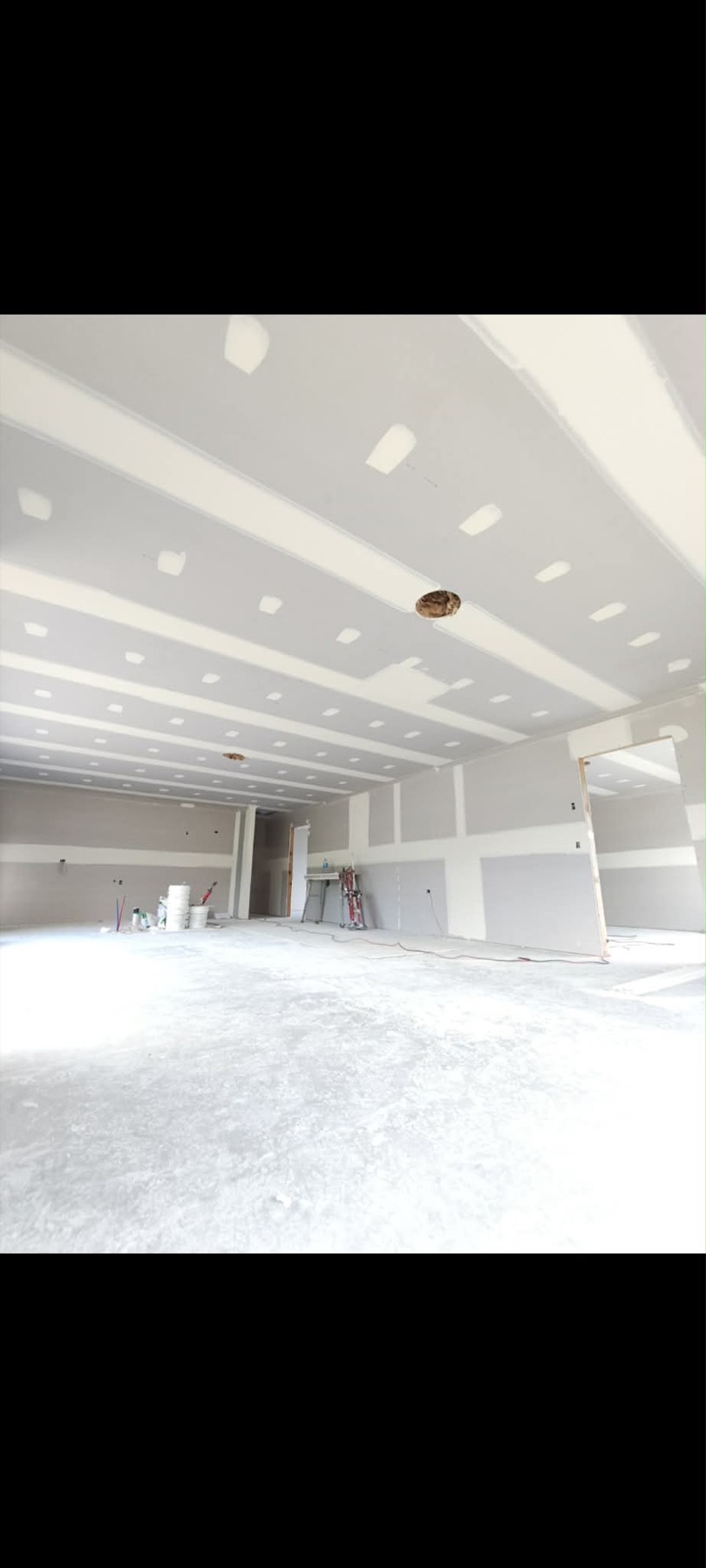 Large interior plasterboard ceiling with repeated stopped panels and clean broad runs.