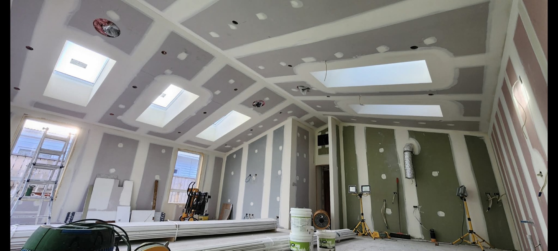 Premium residential ceiling with coffered plasterboard panels and skylight openings in progress.
