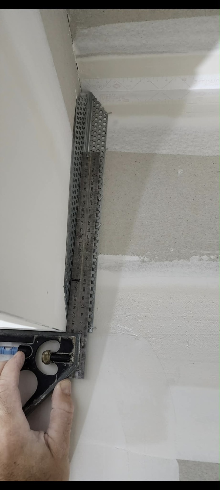 Set square held against a stopped plaster corner to check a straight edge.